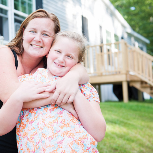 Mom hugging daughter in front of manufactured home